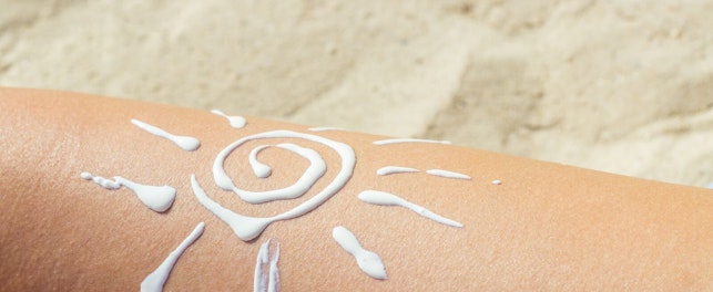 Kosmetyk przeciwsłoneczny ułożony w kształt słońca na skórze.